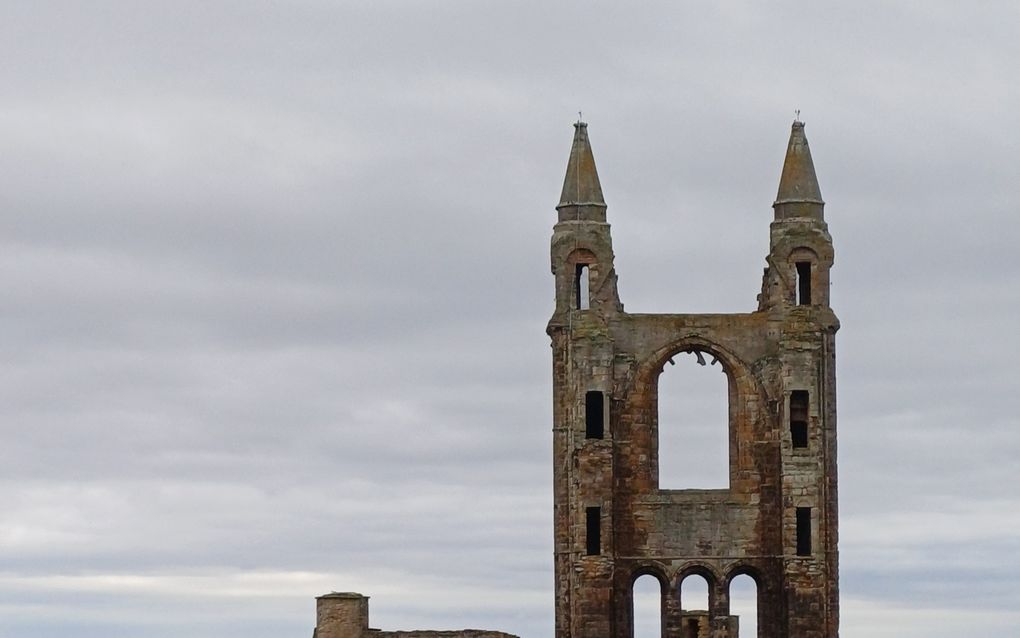 Ruïne van een oude kerk met ervoor een oude begraafplaats.