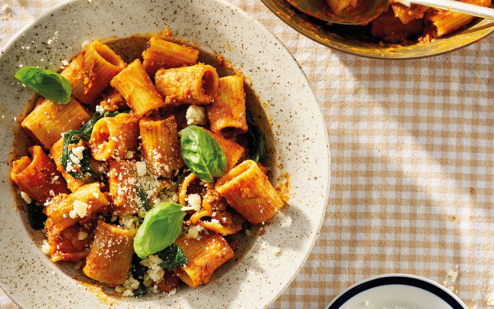 Diep bord met een pastagerecht op een tafelkleed met vichyruitje.
