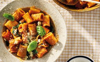 Diep bord met een pastagerecht op een tafelkleed met vichyruitje.