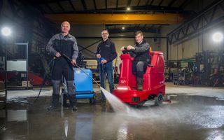 Drie mannen in een loods vol met reinigingsmachines
