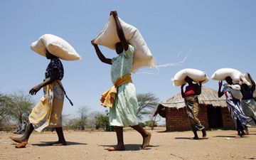 Mensen dragen witte zakken meel op hun hoofd
