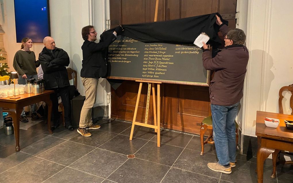 De onthulling van het organistenbord in de Sint-Janskerk in Gouda door Gerben Budding (l.) en Christiaan Ingelse. beeld Muziekcommissie Goudse Sint-Jan