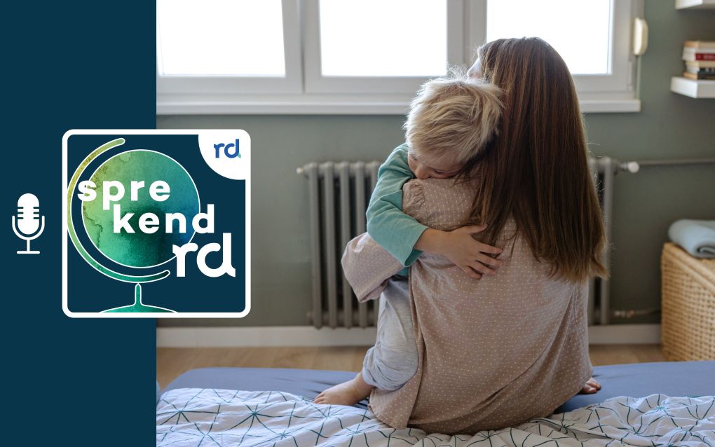 Vrouw die je op haar rug kijkt en op bed zit met een jongetje in haar armen