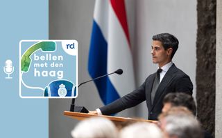 Rob Jetten achter het spreekgestoelte met achter hem de Nederlandse vlag