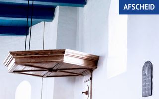 Houten klankbord boven een kansel in een wit kerkinterieur.