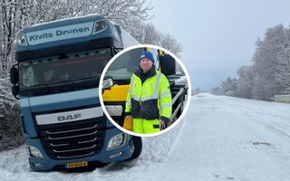 Gestrande vrachtwagen, langs een besneeuwde weg. 