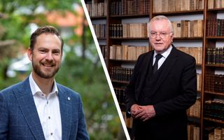 Links dominee Van Olst, een man met blond haar, baardje en blauw colbert, rechts dominee Schot, een man met grijs haar, bril op en gekleed in een zwart pak, staande voor een boekenkast.