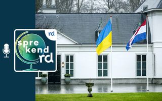 Een blauw-gele Oekraïense vlag en een Nederlandse vlag bij een groot wit huis.