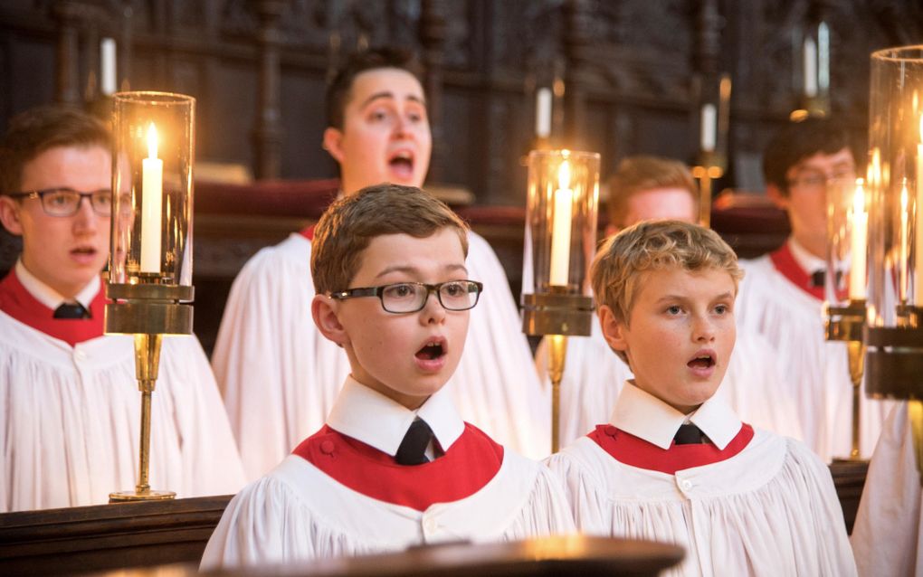 Op de voorgrond twee kleine jongetjes in witte kleding. Ze zingen. Op de achtergrond staan volwassen mannen, die eveneens zingen.