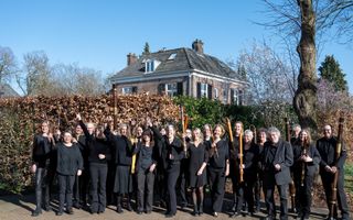 Mensen in zwarte kleding houden een blokfluit omhoog.
