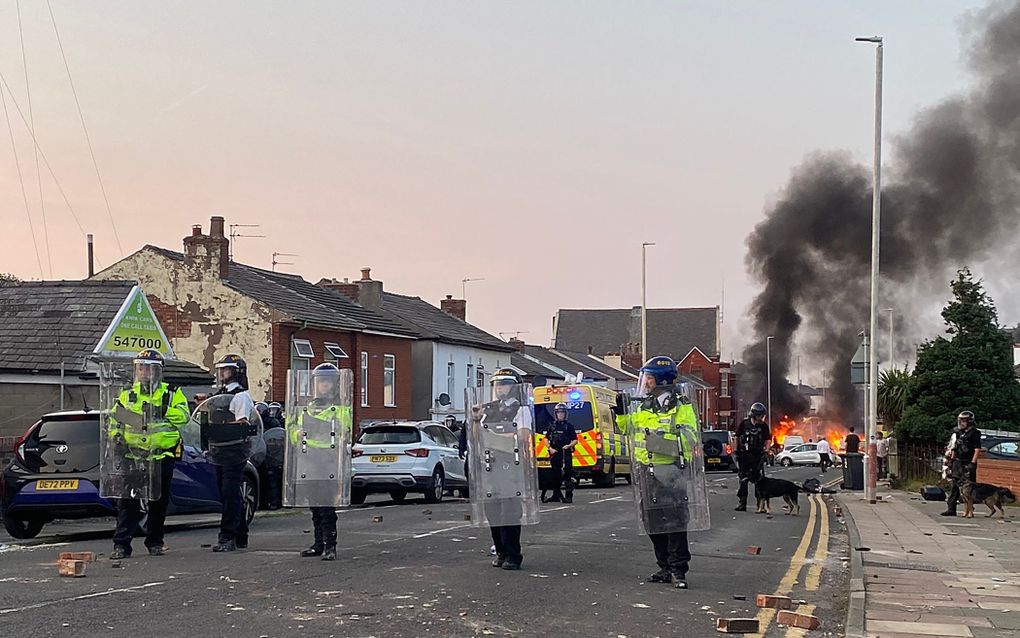 Politieagenten staan dinsdag in de straten van het Noord-Engelse Southport tijdens een anti-immigratiebetoging, nadat een jongeman een dag eerder drie meisjes tijdens een dansles heeft doodgestoken. beeld AFP, Roland Lloyd Parry