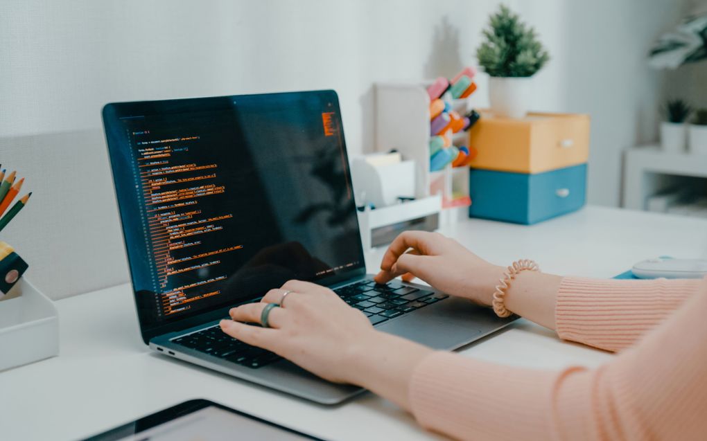 Een meisje zit achter haar bureau, met een laptop daarop.