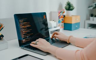 Een meisje zit achter haar bureau, met een laptop daarop.