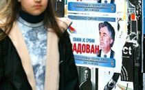 BELGRADO - Een jeugdige inwoonster van Belgrado passeert een poster met daarop een foto van de Bosnisch-Servische Radovan Karadzic, die wordt gezocht in verband met oorlogsmisdaden gepleegd in BosniÃ«. Het Joegoslavische parlement nam op 10 april een wet 