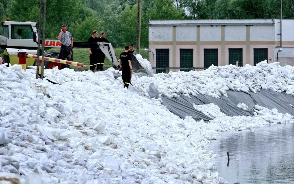 WARSCHAU - Brandweerlieden zijn in een Pools dorp bezig met zandzakken om het water in te dammen. In Warschau gaan scholen dicht vanwege het gestegen waterpeil. Foto EPA