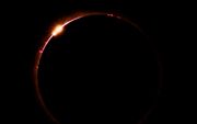 Terwijl de maan tijdens een totale zonsverduistering in Noord-Amerika voor de zon langs beweegt, schieten de zonnevlammen goed zichtbaar de ruimte in. beeld AFP, Josh Edelson