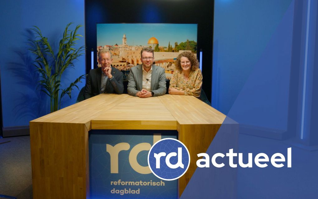 Twee heren en een vrouw zitten aan een houten tafel.