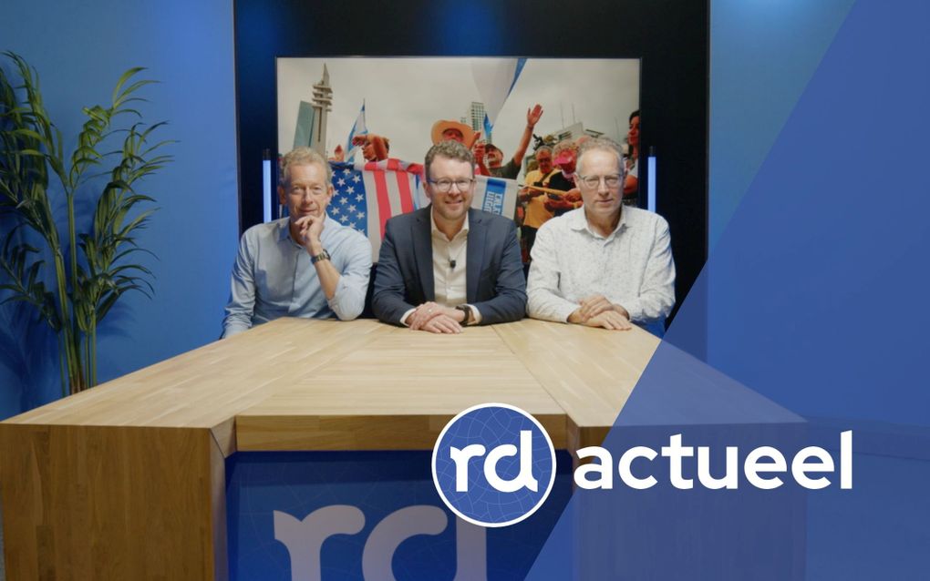 Drie mannen zitten aan een houten tafel.