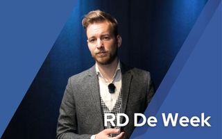 Netjes geklede man staat voor blauwe achtergrond.