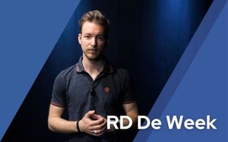 Man in donkere polo staat voor een donkerblauwe achtergrond.