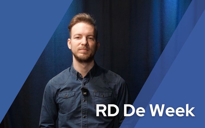 Een jongeman voor een blauwe achtergrond.