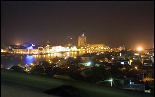 Willemstad bij nacht, met verlichte woningen, aan een rivier.