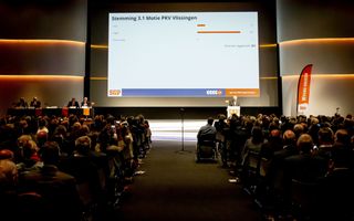 Een zaal met mensen en een groot scherm