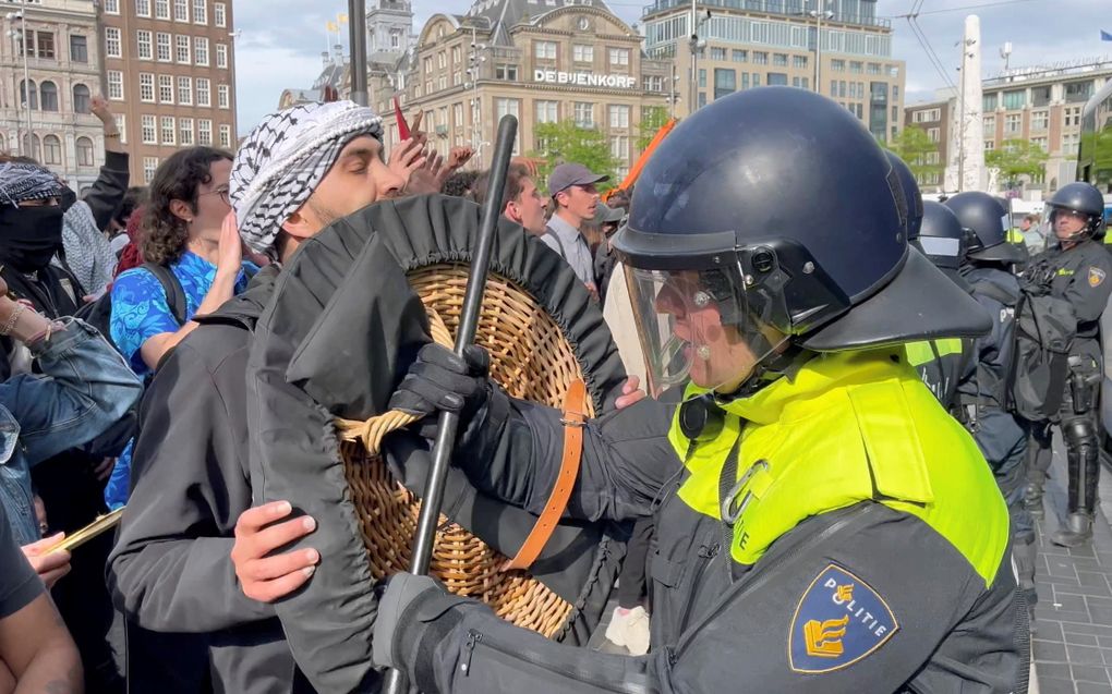 Een ME’er duwt een pro-Palestijnse demonstrant bij een betoging op de Dam. beeld RD