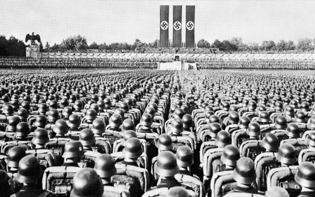 Duitse soldaten voor een podium, op de achtergrond nazivlaggen.