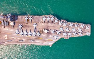 Een Amerikaans vliegdekschip, volledig beladen met gevechtsvliegtuigen, op een groenachtige zee.