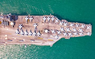 Een Amerikaans vliegdekschip, volledig beladen met gevechtsvliegtuigen, op een groenachtige zee.