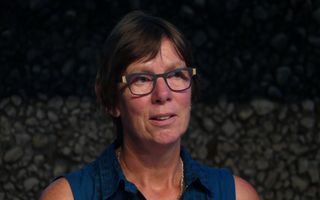 Portret van een vrouw van middelbare leeftijd met bril en kort, donker haar.