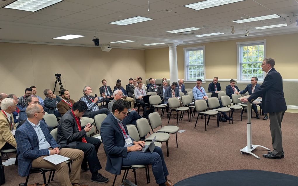 Een man spreekt voor een zittende groep mensen.