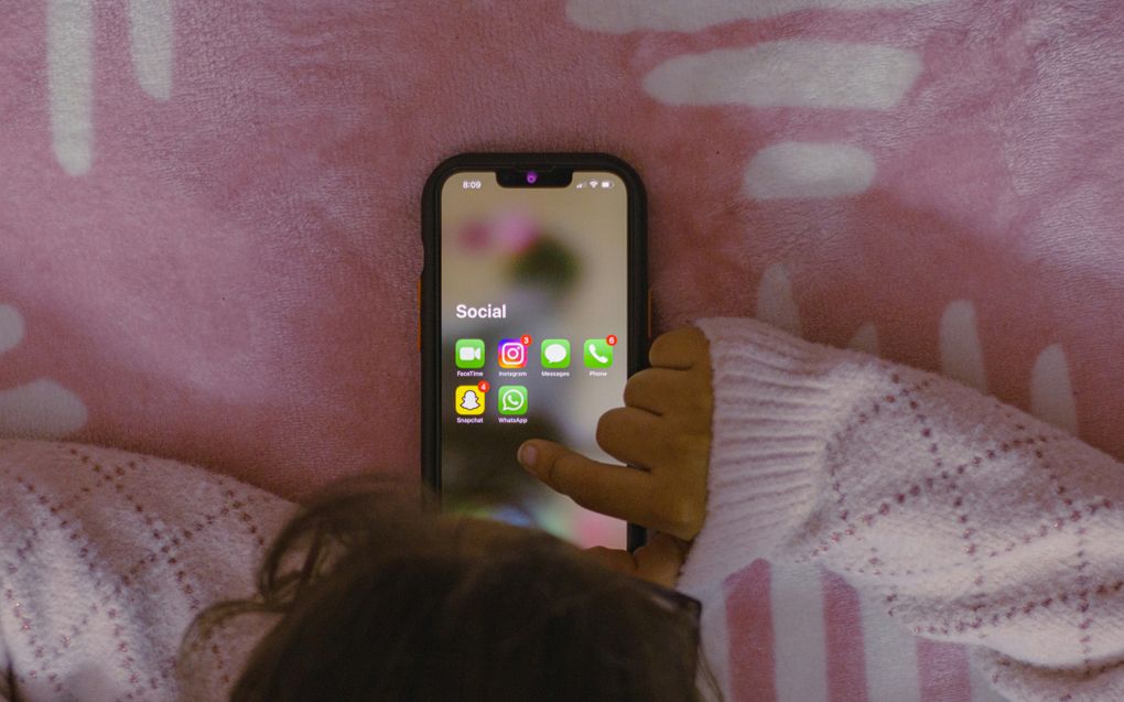 Een meisje kijkt op haar iphone naar socialemediaapps.