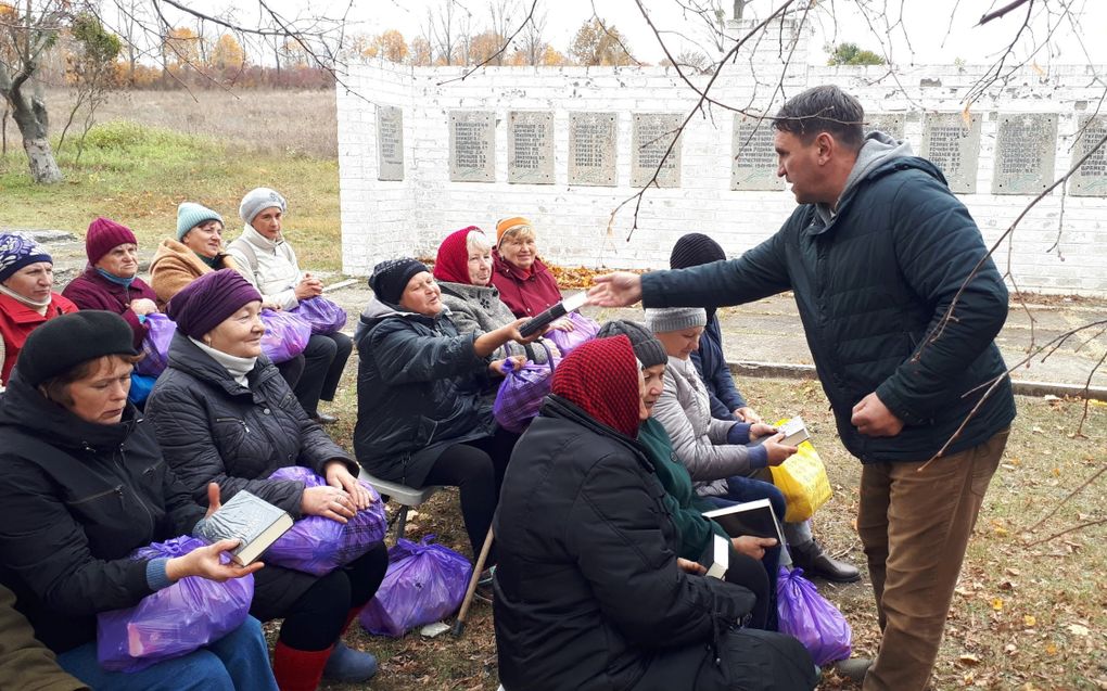 Een man deelt bijbels uit aan bezoekers van een openluchtsamenkomst in Oekraïne.