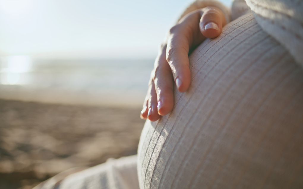 Een vrouw legt haar hand op het kindje in haar buik