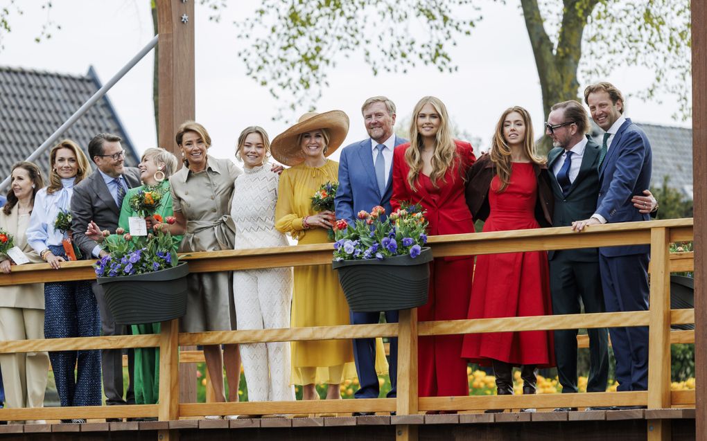 De koninklijke familie staat op een rijtje, op een houten brug met daarop twee bloembakken met viooltjes en tulpen.