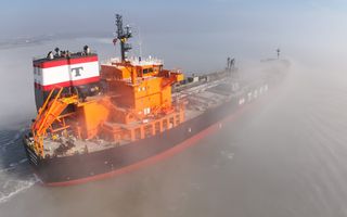 Een oranje en zwart gekleurde olietanker vaart over de Westerschelde.