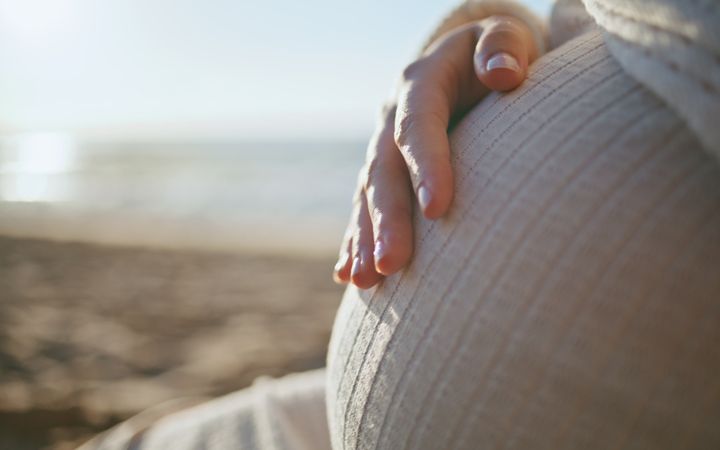 Een vrouw legt haar hand op het kindje in haar buik