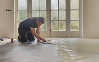 Vloerenlegger legt vloer in een woonkamer met openslaande deuren