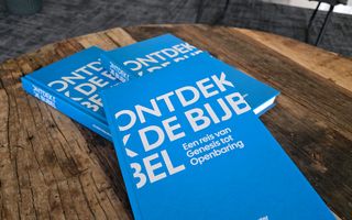 Drie boekjes met een blauwe kaft op een houten tafel. Op de kaft staat: ”Ontdek de Bijbel. Een reis van Genesis tot Openbaring”. 