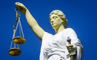 Vrouwe Justitia, een standbeeld van een vrouw met gesloten ogen die een weegschaal omhooghoudt en een zwaard vasthoudt.