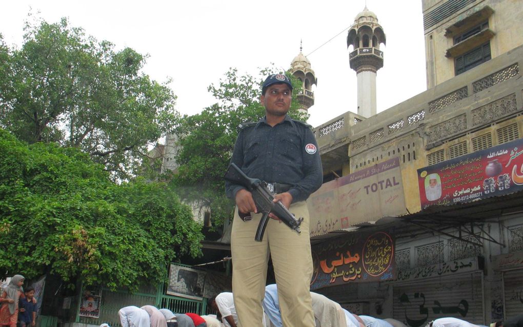 Een politieman bewaakt moskeegangers in Faisalabad. Foto EPA