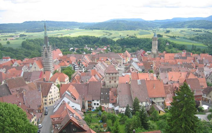 Luchtfoto van een kleine Duitse stad. Op de voorgrond roodbruine daken, met daar bovenuit stekend twee kerktorens. Op de achtergrond een heuvellandschap met bossen en akkers.