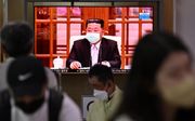 Kim Jong Un met mondkapje is te zien op televisieschermen. Beeld AFP, Anthony WALLACE