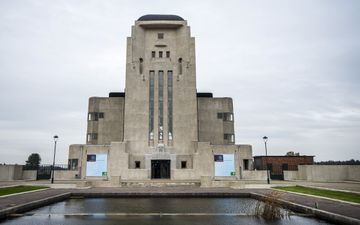 Groot, stenen gebouw met een vijver ervoor. 