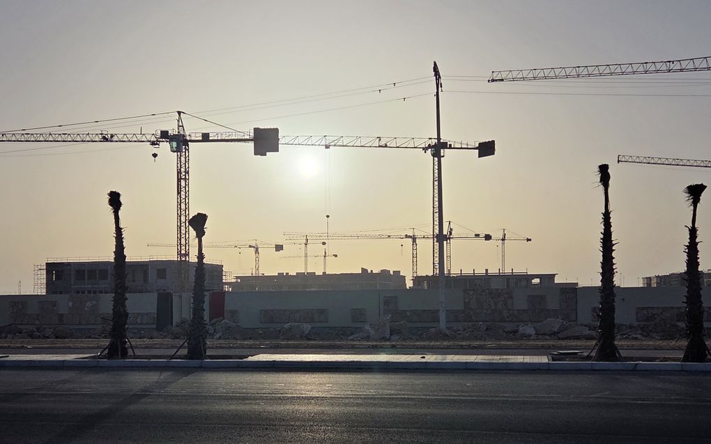 Gele bouwkranen torenen boven half afgebouwde betonnen gebouwen uit.
