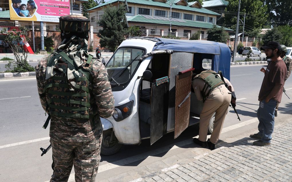 Indiase militairen houden de wacht terwijl een politieagent een autoriksja controleert in Kasjmir. In de regio zijn grote spanningen na een terreuraanslag vorige week. beeld EPA, Farooq Khan