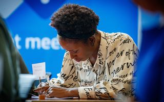 Schrijvende vrouw in lichte outfit.