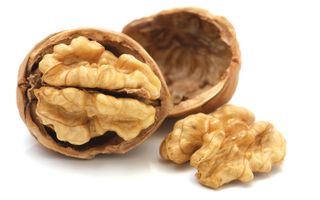 Een walnoot in twee helften. In de linkerhelft zit de noot nog; de rechterhelft is leeg, de noot ligt ernaast.